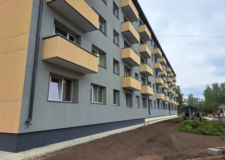 Фасад многоквартирного дома с серой отделкой и жёлтыми балконами, двор