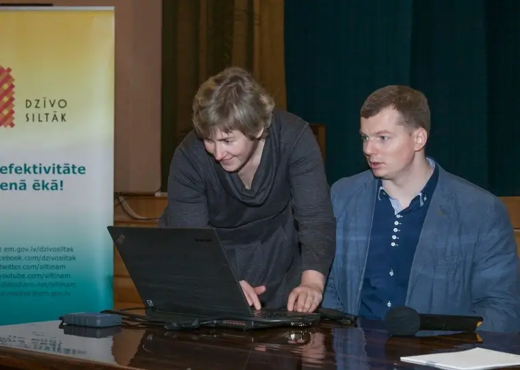 Dzīvo siltāk event, energy efficiency presentation next to a laptop