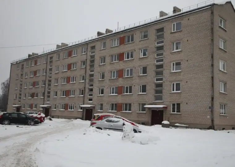 Piecu stāvu daudzdzīvokļu māja ar ķieģeļu fasādi un logu rindām, ziemas skats