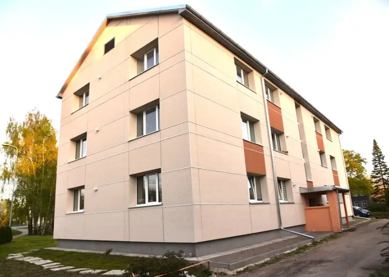 Renovated apartment building with an insulated beige facade and orange accents