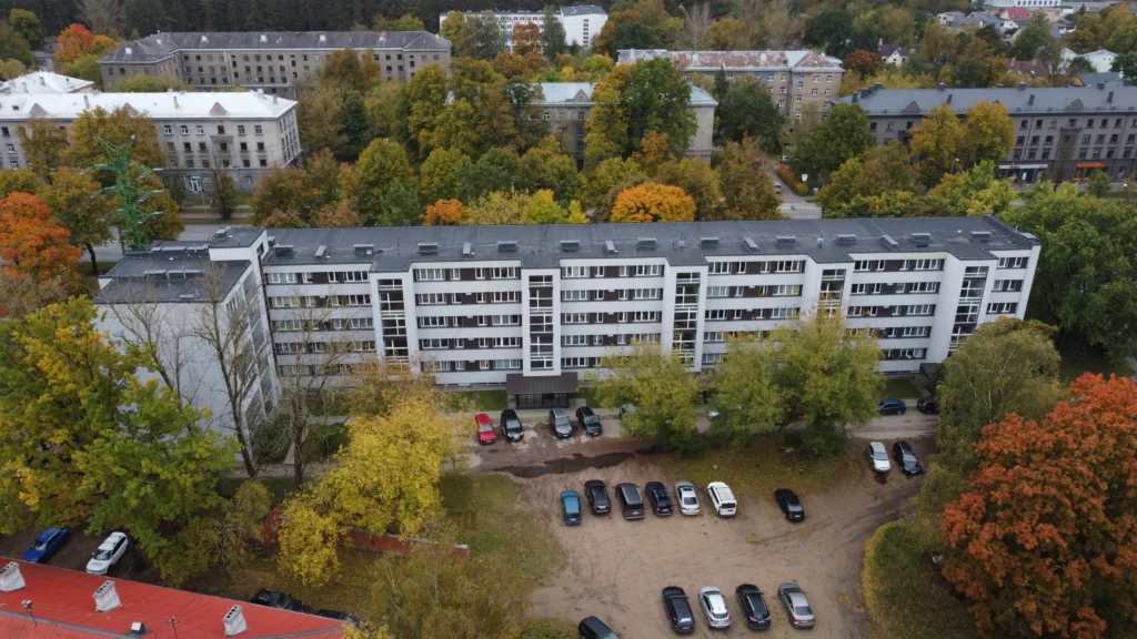 Gara daudzstāvu daudzdzīvokļu ēka ar gaiši pelēku fasādes apdari un plakanu jumtu, Rīga