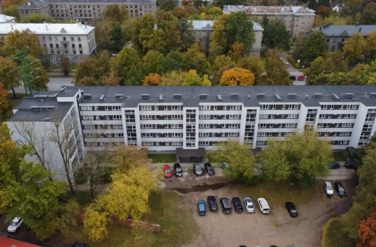 Aerial view of an apartment building with a light facade, grey roof and parking, Riga
