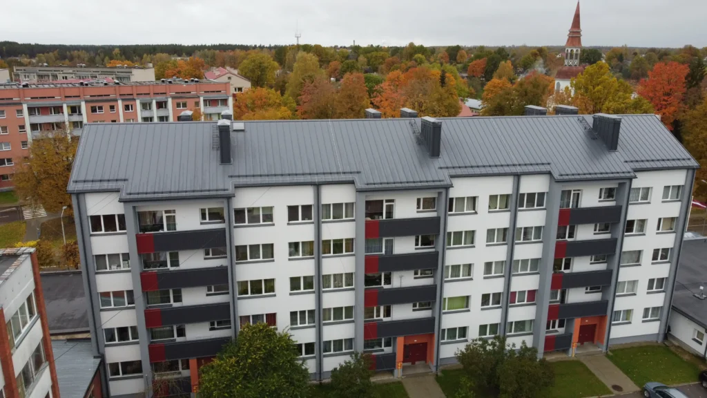 Renovated 5-storey apartment building, building 1 with a white and grey facade, dark grey and red accents, and a dark grey metal roof