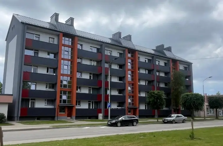 Apartment building with a grey facade, orange accents and balconies, street view