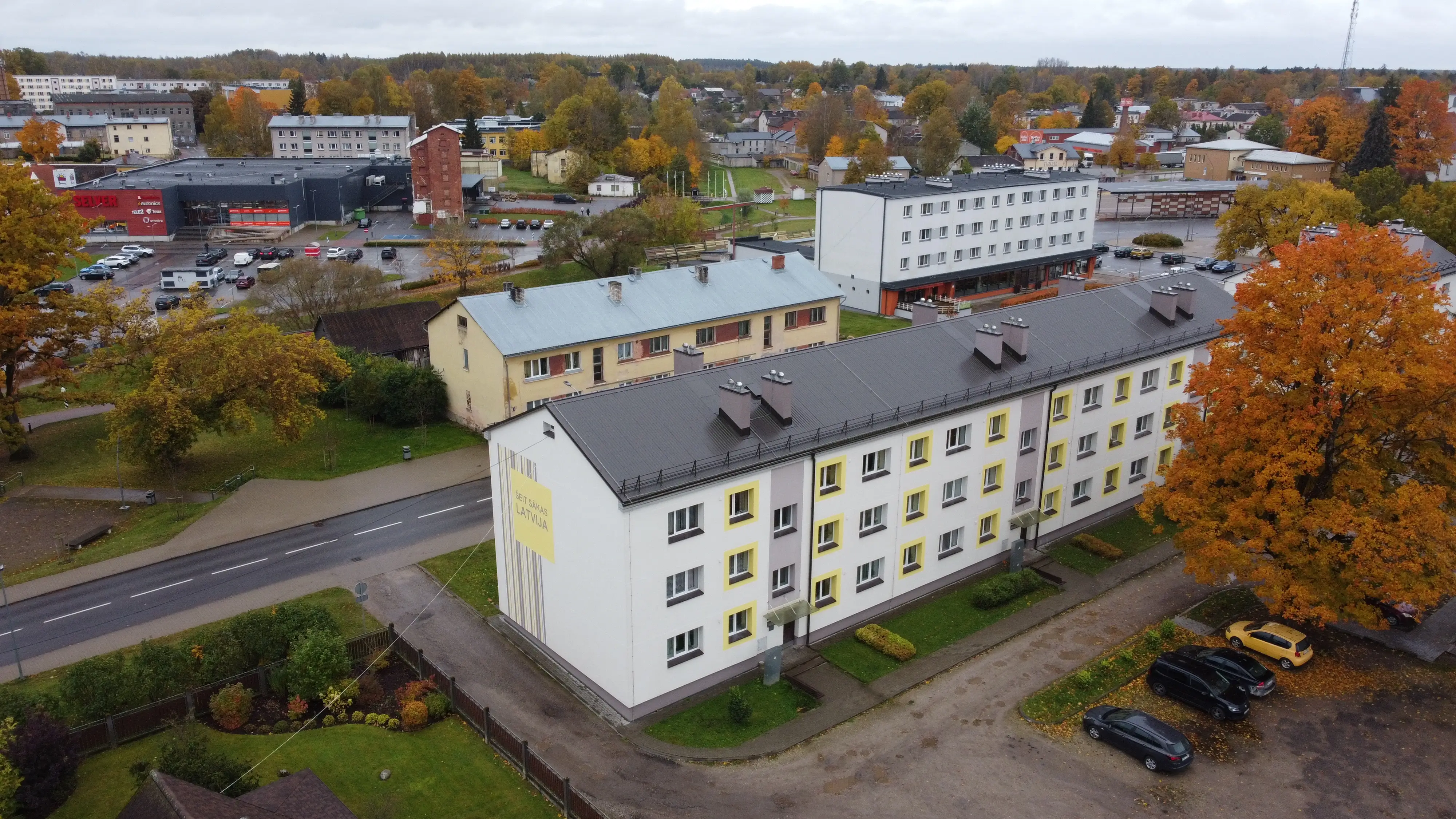 3-storey apartment building with a white facade, yellow window frames and a grey roof, Valka