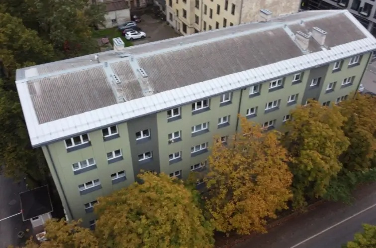 Вид сверху на многоквартирный дом с зелёным фасадом и крышей, Рига