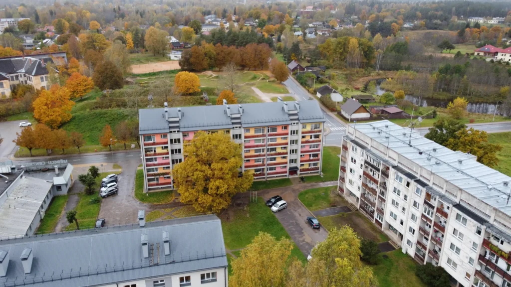 5 storey apartment building with a colorful facade and metal roof, drone view