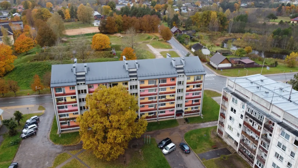 5 storey apartment building with a colorful facade and metal roof, drone view