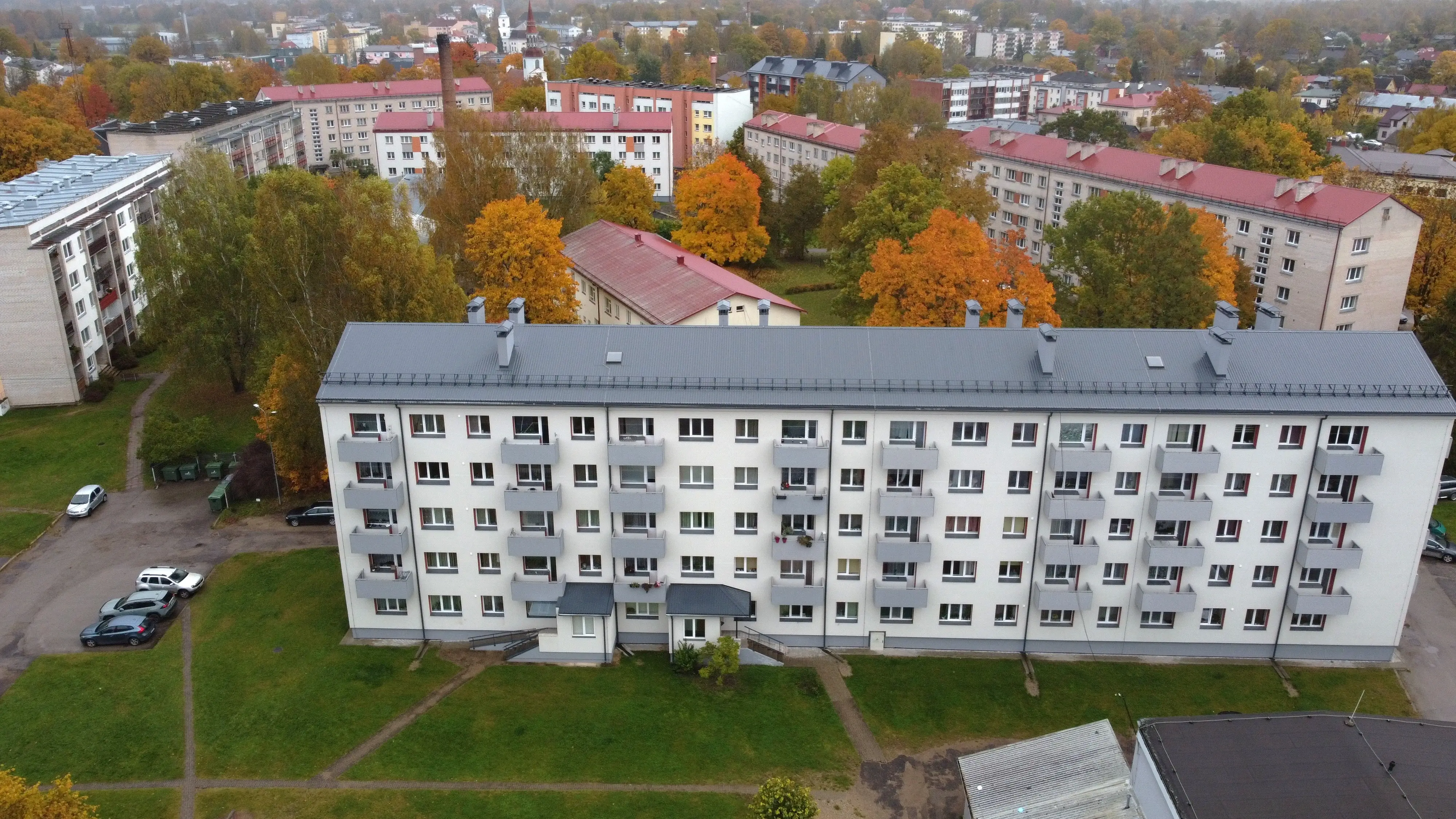 5 stāvu daudzdzīvokļu ēka ar baltu fasādes apdari, pelēku jumtu un balkoniem, Valka