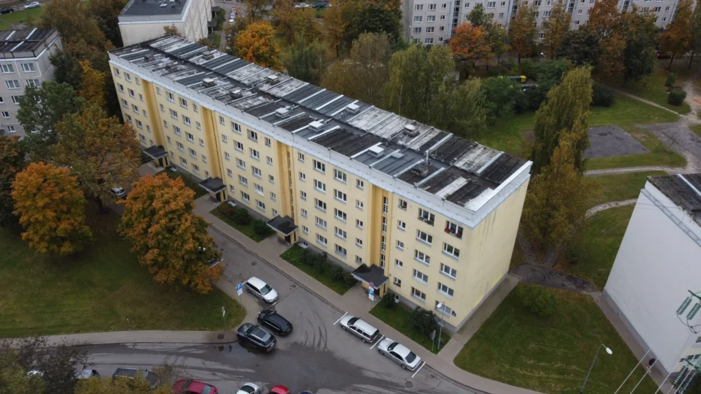 5 stāvu daudzdzīvokļu māja ar dzeltenu fasādi, baltiem logiem un plakanu jumtu