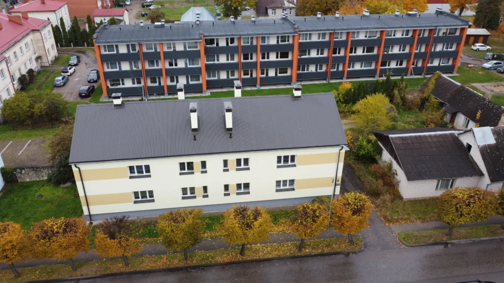 Divas daudzdzīvokļu ēkas ar gaišu fasādes apdari, tumši pelēku jumtu un oranžām vertikālām joslām, Valka