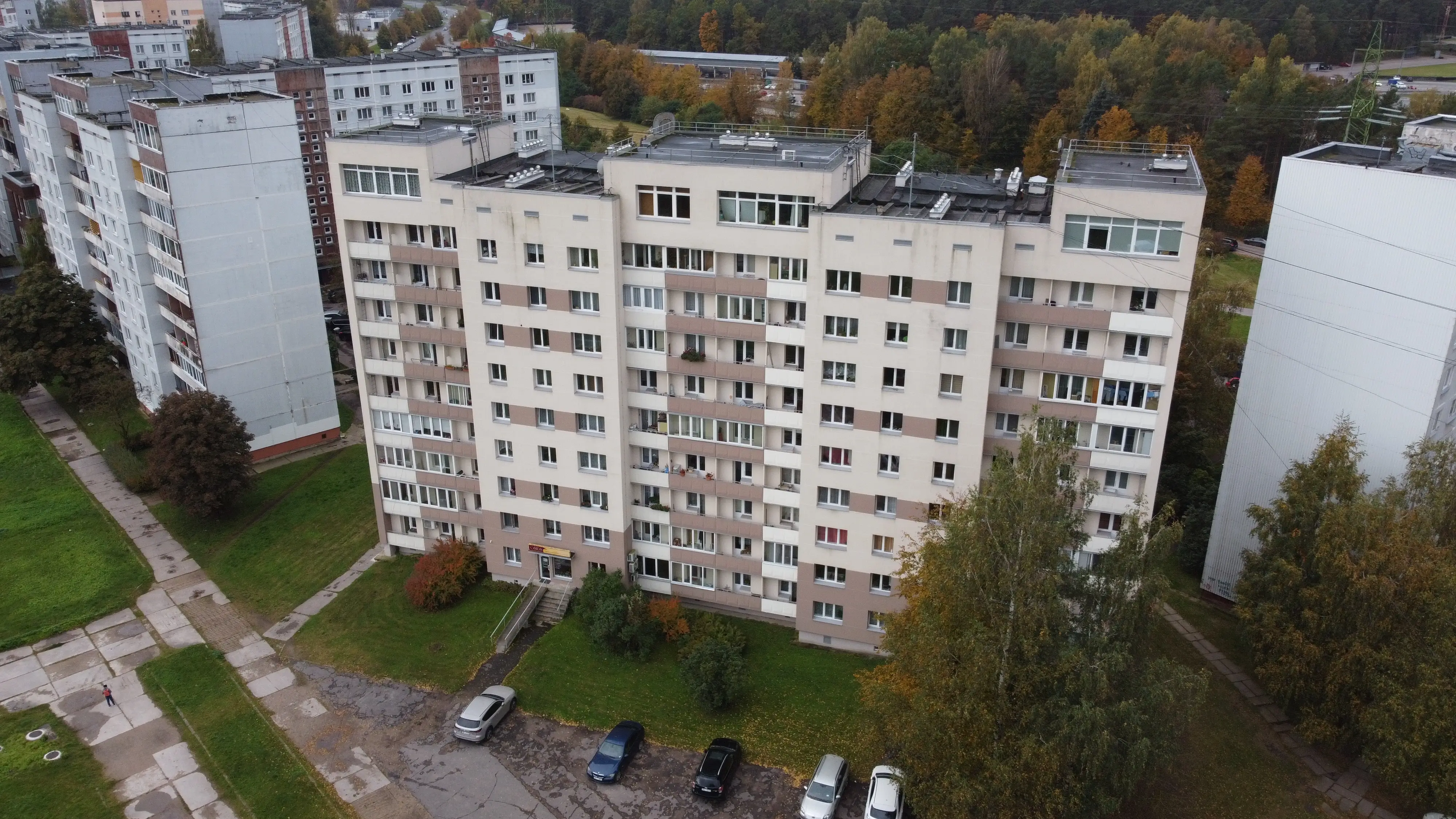 9 stāvu daudzdzīvokļu ēka ar baltu fasādi, balkoniem un melnu plakano jumtu