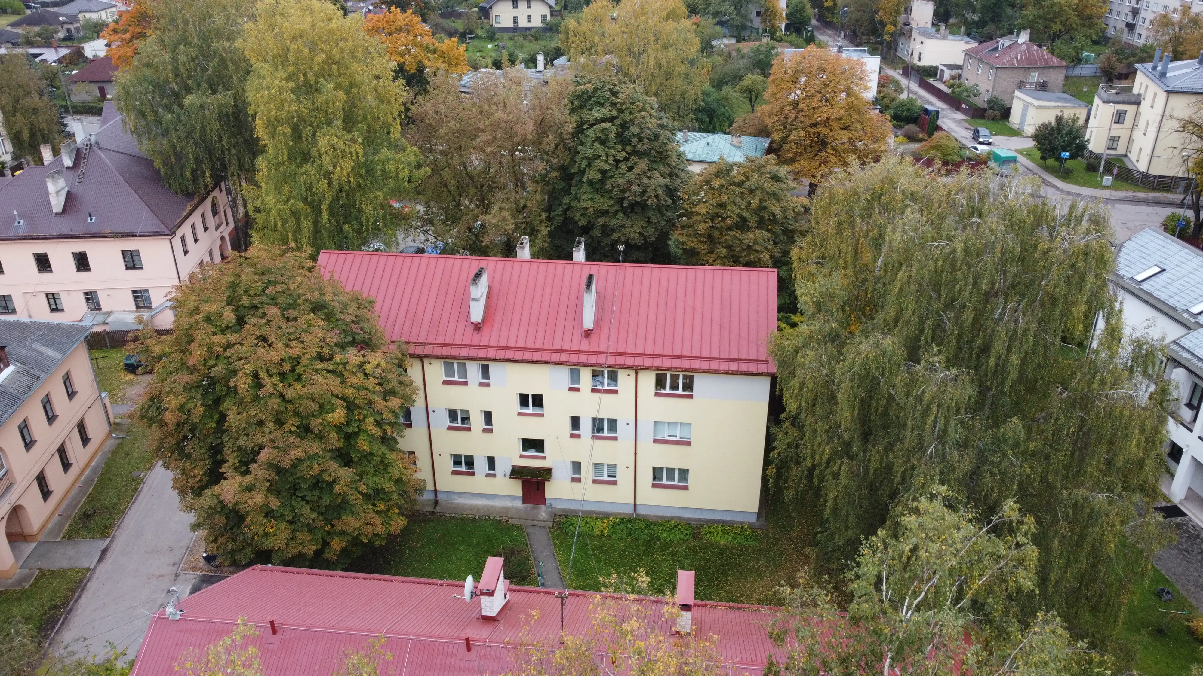 Trīsstāvu daudzdzīvokļu ēka ar siltinātu krēmkrāsas fasādes apdari un sarkanu skārda jumtu, Rīga