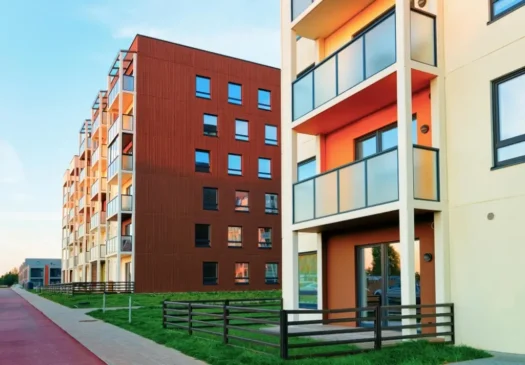 Apartment building complex with brown cladding, glass balconies and landscaped surroundings