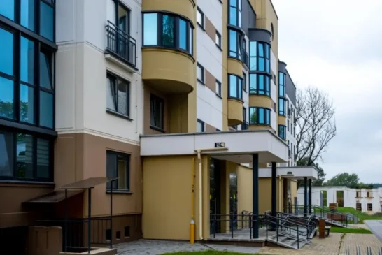 Apartment building entrance with a canopy, balconies and glazed loggias