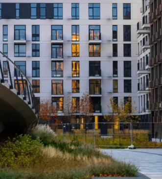 Modern apartment building facade with windows and balconies, courtyard landscaping
